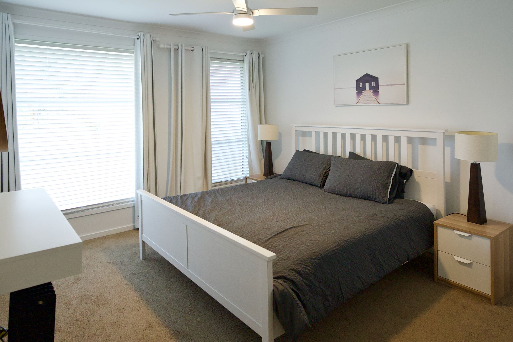 Queen bedroom with soft linen and a framed boat house print